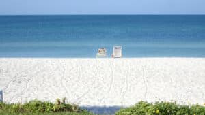 People relaxing in chairs on a beach, one of the best Longboat Key attractions.