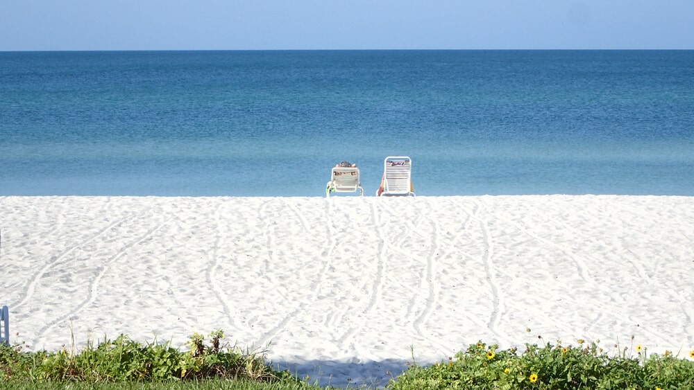 People relaxing in chairs on a beach, one of the best Longboat Key attractions.