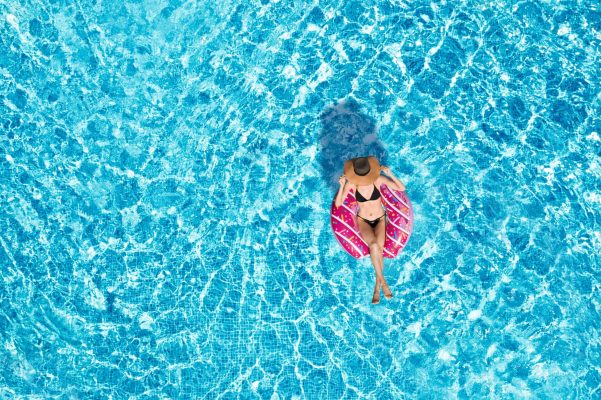 Young,Happy,Woman,With,Inflatable,Ring,In,Swimming,Pool,,Top
